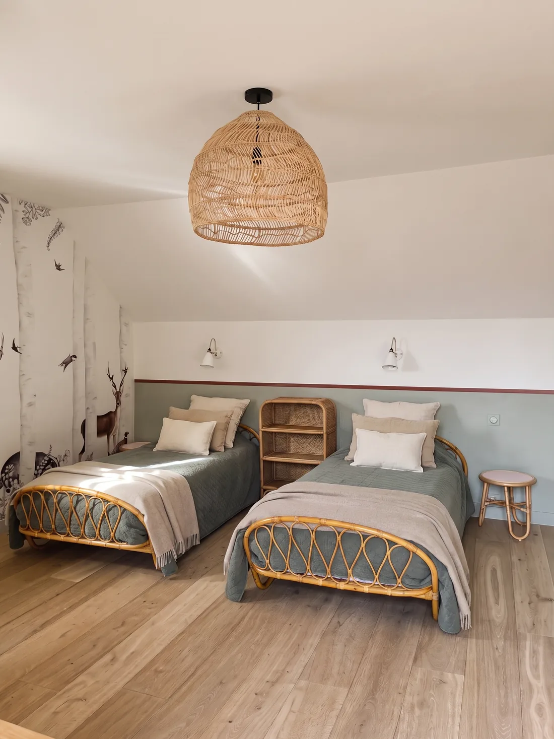 L'autre bout de la chambre des enfants, sous les combles : les deux lits de rotin cintré, étagère de rotin entre les deux, soubassement vert sauge à liseré bordeaux et grande suspension d'osier