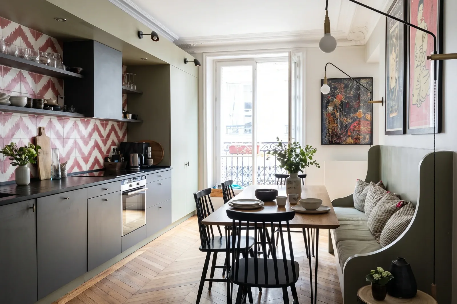 Cuisine et coin repas décorés dans un appartement haussmannien parisien : placards vert amande, credence à carreaux, table et chaises choisies pour le lieu