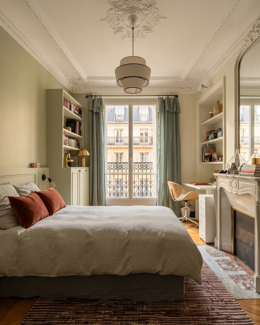 Tête de lit lambrissée vert amande : applique noire à ampoule apparente, affiche japonisante d'arbre en fleurs encadrée de chêne et coussin de velours terracotta